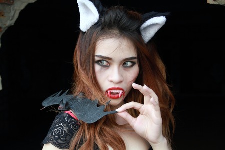 Beautiful Young woman as sexy vampire - halloween portrait on dark backgroundの写真素材