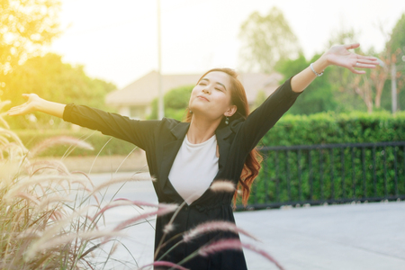 blurry of Successful business woman with arms up and Happy celebrating winning success woman at sunset or sunrise standing elated with arms raised up above her head in celebration の写真素材