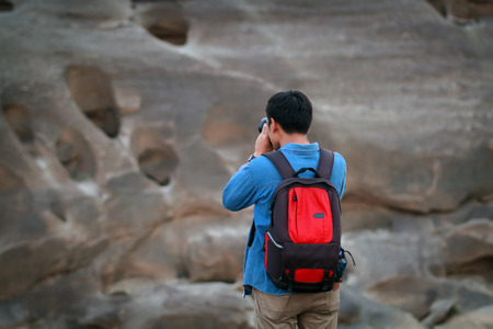 A man asia with backpack taking a photo on the top of mountains ,soft focusの写真素材