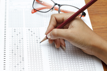 hand of women holding pencil on Standardized test form with answers bubbled in and a pencil, focus on answer sheetの写真素材