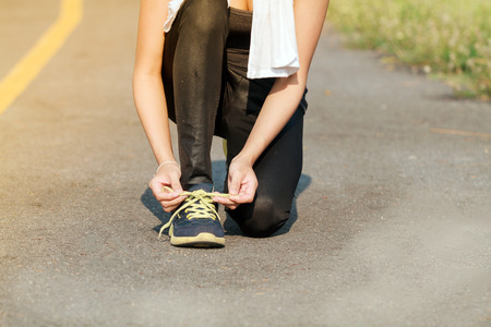 women asia sport, fitness, exercise and lifestyle concept - runner woman lacing trainers shoesの写真素材
