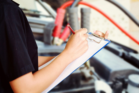 Portrait of smiling young female mechanic inspecting on a car in auto repair shopの写真素材