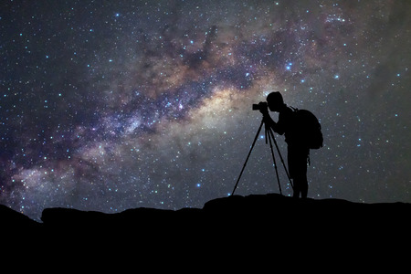 silhouette  of man photography take a photo of Milky Way galaxy on dark night at thailandの写真素材