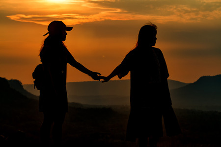 Silhouette couple's holding hand for travelers on sunriseの写真素材