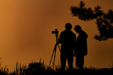 silhouette two man asia with backpack taking a photo on the top of mountains ,soft focus