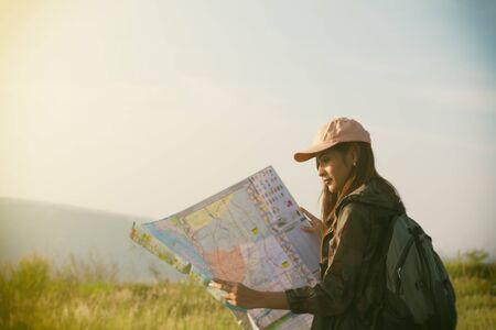 Women asian with backpack enjoying sunset on peak of mountain, looking map. Tourist traveler on background mountain landscape and sunlight in tripの写真素材