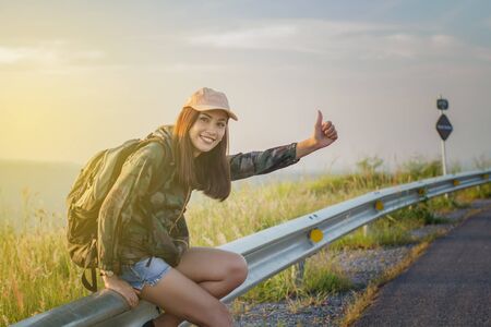 Asian women tourists and backpackers waiting car at the roadside.の写真素材