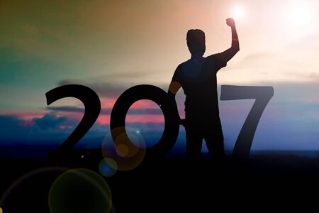 silhouette of men show arm up for achievements successful and celebrating success on sunset and 2017 years while celebrating new yearの写真素材