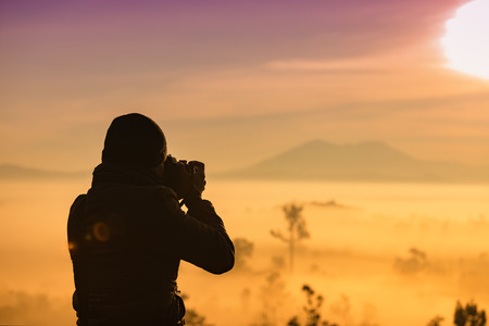 silhouette of asian  photography take a photo of Beautiful gold sunrise and Foggy clouds in forest at Thung Salaeng Luang National Park,Thailandの写真素材