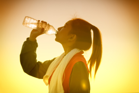 blurred image of Sporty Asian woman drinking water outdoor