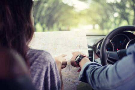 Asian man and woman using map on road trip and Happy young couple with a map in the car. Blurred and...