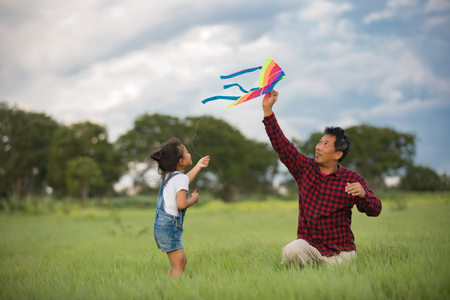 Asian child girl and father with a kite running and happy on meadow in summer in natureの写真素材