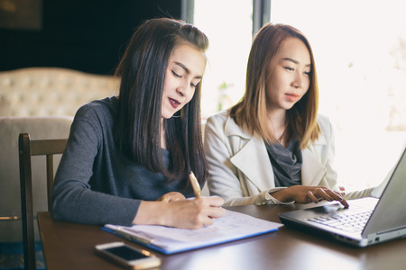 Two Asian business women using notebook working and Discussion of the important contract at office ,soft focusの写真素材