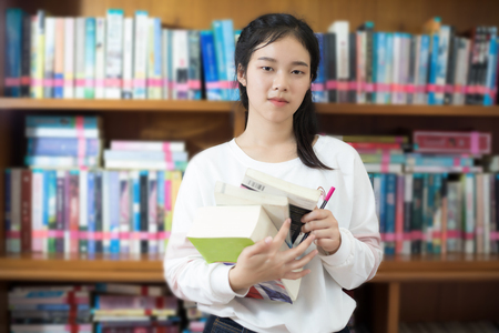 Asian female students holding for selection Book  in libraryの写真素材