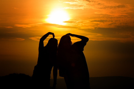 Silhouette of couple in love watching a sunset on the mountains, moment of reflectionの写真素材