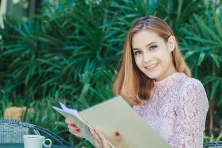 Asian business women smiling  working and writing a book and checking document at outdoor ,soft focusの写真素材