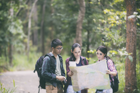 Asian Group of young people Hiking with friends backpacks walking together and looking map and taking photo camera by the road and looking happy ,Relax time on holiday concept travelの写真素材