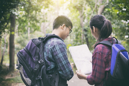 Asian Group of young people Hiking with friends backpacks walking together and looking map and taking photo camera by the road and looking happy ,Relax time on holiday concept travelの写真素材