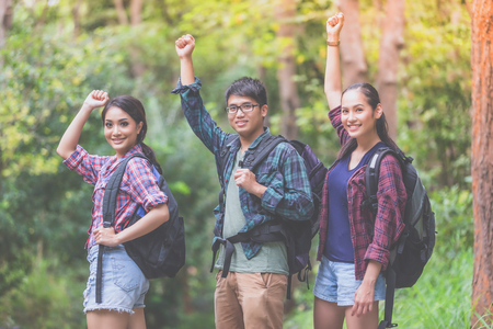 Asian Group of young people Hiking with friends backpacks walking together and looking map and taking photo camera by the road and looking happy ,Relax time on holiday concept travelの写真素材