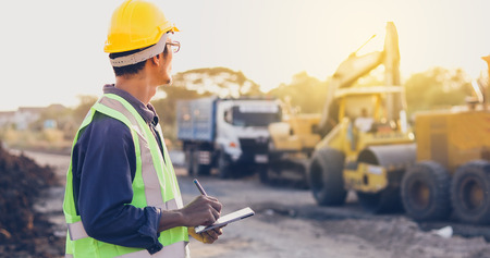 Asian engineer with hardhat using  tablet pc computer inspecting and working at construction site