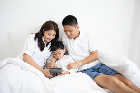 family and son watching and  play tablet on bedの写真素材