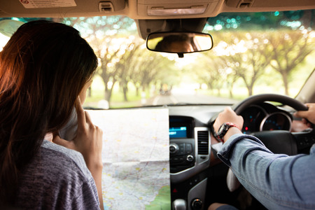 Asian man and woman using mobile on road trip and Happy young couple with a map in the car. Blurred and Soft focusの写真素材