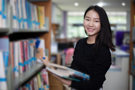Asian female students holding for selection Book  in libraryの写真素材