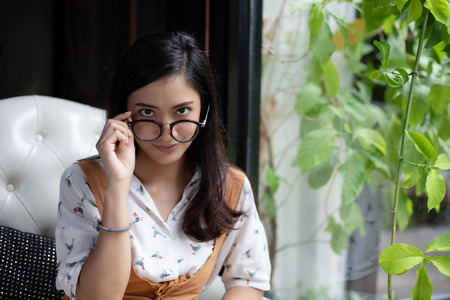 Asian women are holding glasses and smiling at a coffee shop on a holiday.の写真素材