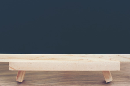 Black board on wood table top with sun and blur green tree bokeh background, Template mock up for display of productの写真素材