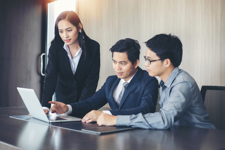 Asian businessmen and group using notebook for business partners discussing documents and ideas at meeting and business women smiling happy for workingの写真素材
