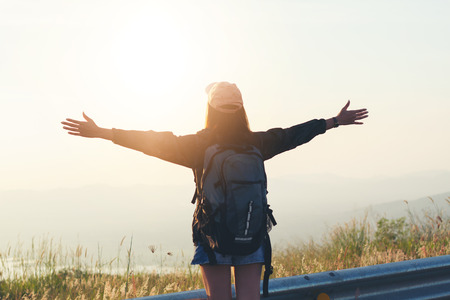 Freedom traveler woman standing with raised arms and enjoying a beautiful nature and cheering young...