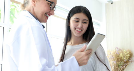Doctor meeting and explaining medication to woman patient in his office at Hospitalsの写真素材