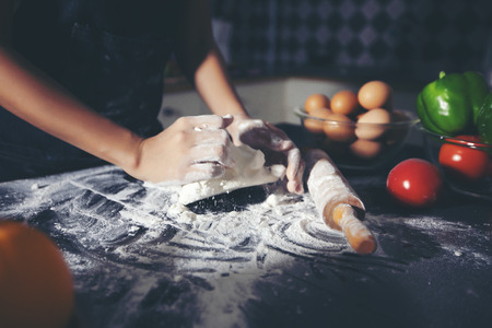 Asian women preparing a pizza, knead the dough and puts ingredients on kitchen tableの写真素材