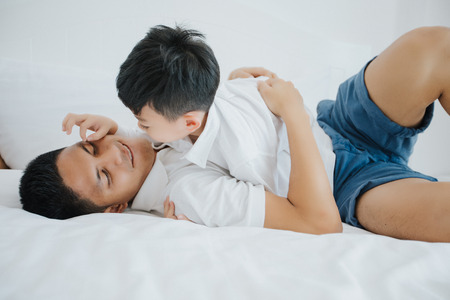 Happy Asian family with son at home on the bedroom playing and laughing