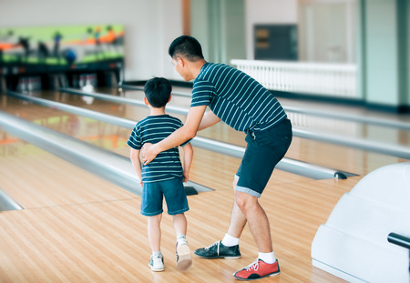 Father teaching son for play bowling at bowling clubの写真素材