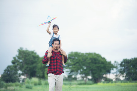 Asian child girl and father with a kite running and happy on meadow in summer in natureの写真素材