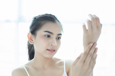 A beautiful woman asian using a skin care product, moisturizer or lotion taking care of her dry complexion. Moisturizing cream in female hands .の写真素材