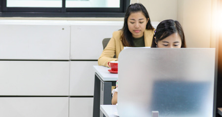 Asian businesswoman serious about the work and using notebook for business partners discussing...