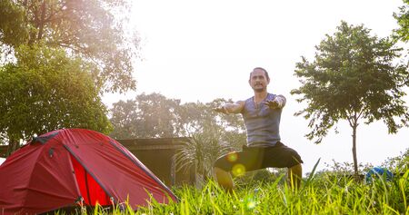 A man exercise and Athlete Warming Up in morning near tent on camping trip on the mountainの写真素材