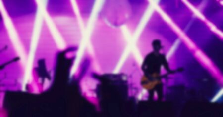 silhouettes of concert crowd at Rear view of festival crowd raising their hands on bright stage lightsの写真素材