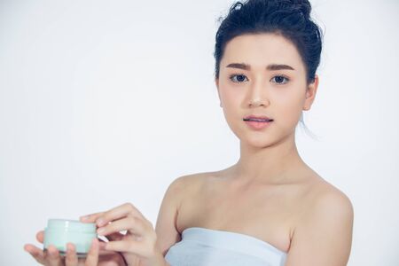 A beautiful woman asian using a skin care product, moisturizer or lotion taking care of her dry complexion. Moisturizing cream in female hands .の写真素材