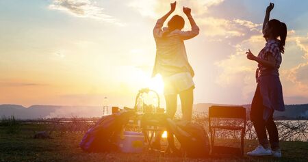 group of Asian friends tourist drinking and dancing together with happiness in Summer while having camping near lakeの写真素材