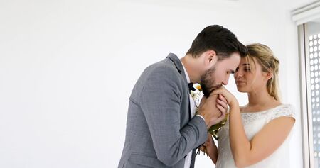 The lovers give flowers to the bride and kissed happy and couple love standing in wedding studioの写真素材