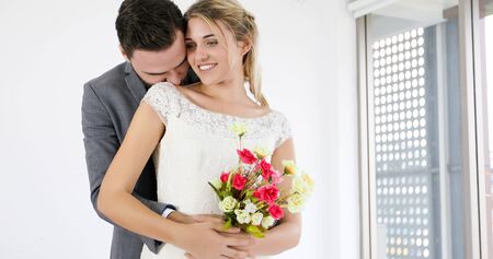 The lovers give flowers to the bride and kissed happy and couple love standing in wedding studio
