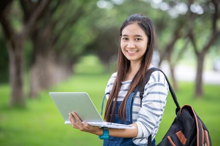 beautiful Asian girl student holding books and smiling at camera and learning and education concept ...