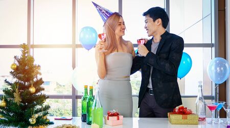 Asian Couple lover having party with alcoholic beer drinks and Young people enjoying at a bar toasting cocktails with Christmas gift in Christmas holiday and happy new year pattyの写真素材
