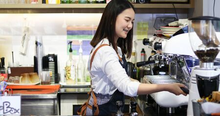 Asian women Barista smiling and using coffee machine in coffee shop counter - Working woman small business owner food and drink cafe conceptの写真素材