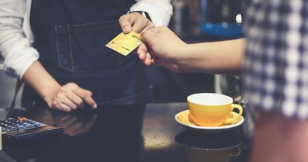 Barista serving customer and Woman is paying for coffee by credit card in coffee shop