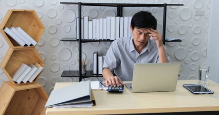 A senior Asian man using notebook for working and businesswoman serious about the work done until the headacheの写真素材