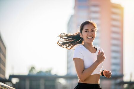 Asian Young fitness sport woman running  and smiling on city road
